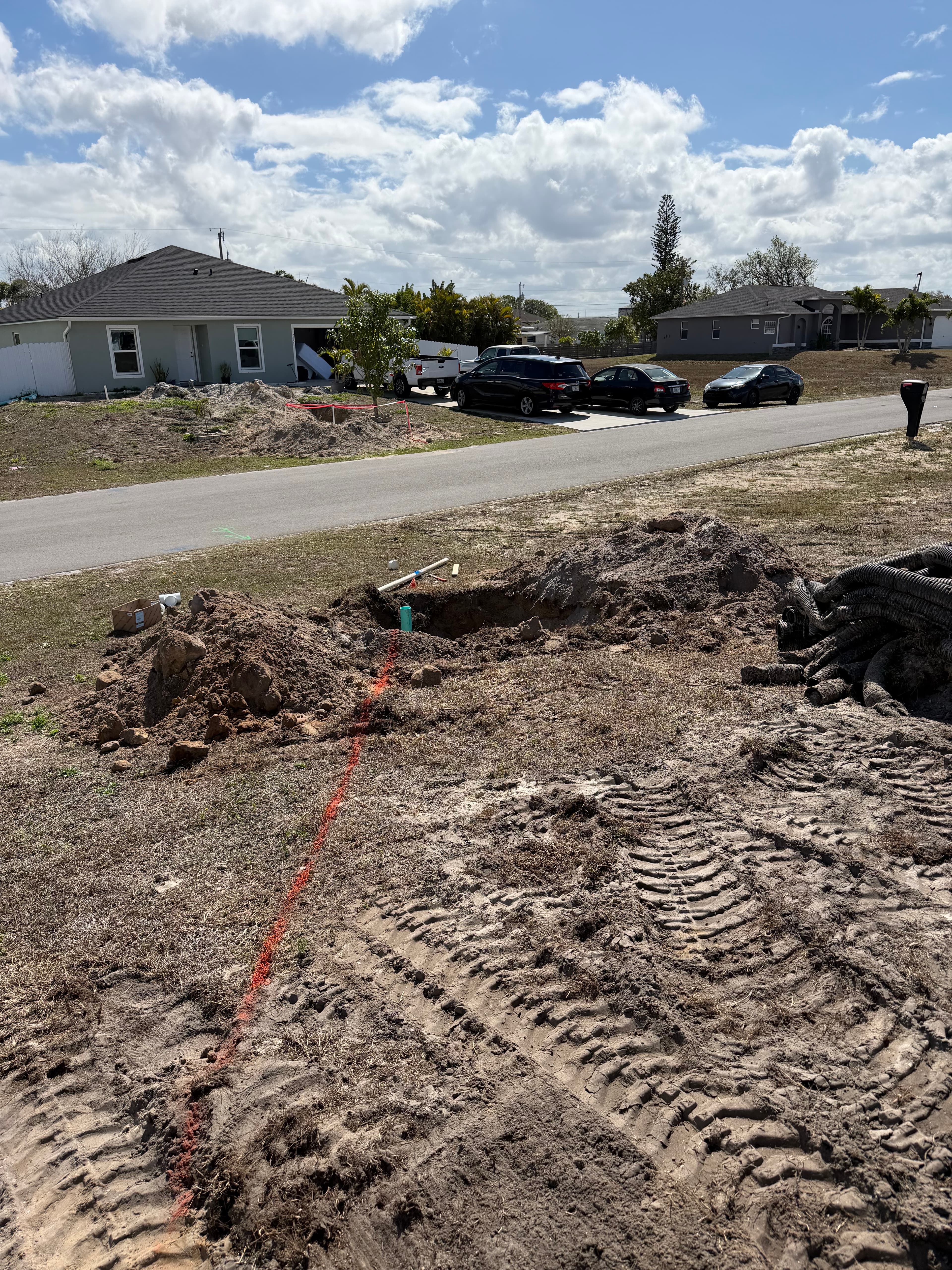 Sewer line trench with new green sewer pipe and orange locate line for UEP utility hookup