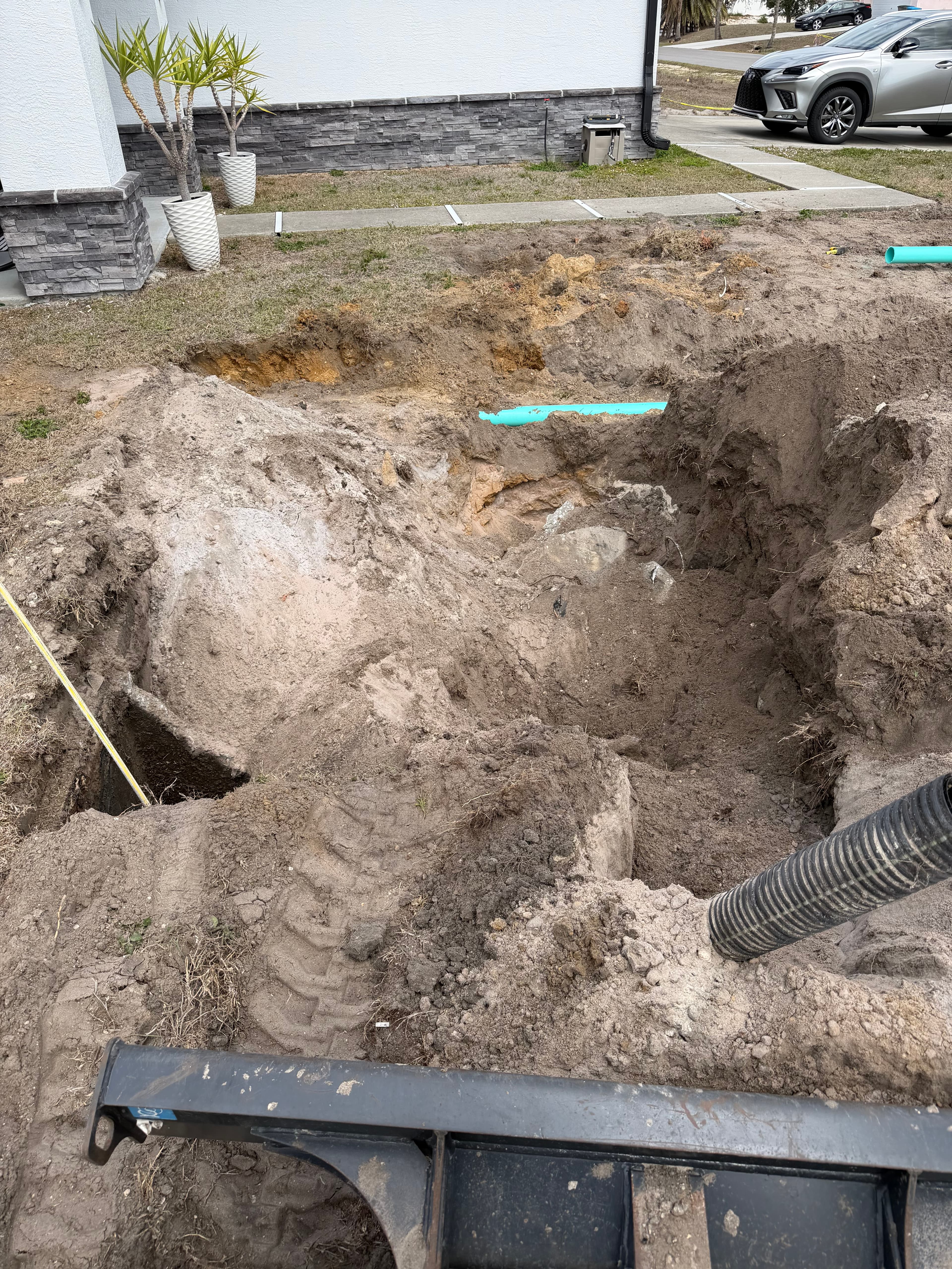 Deep trench excavation with green sewer pipe connection at residential property — mini excavator on site