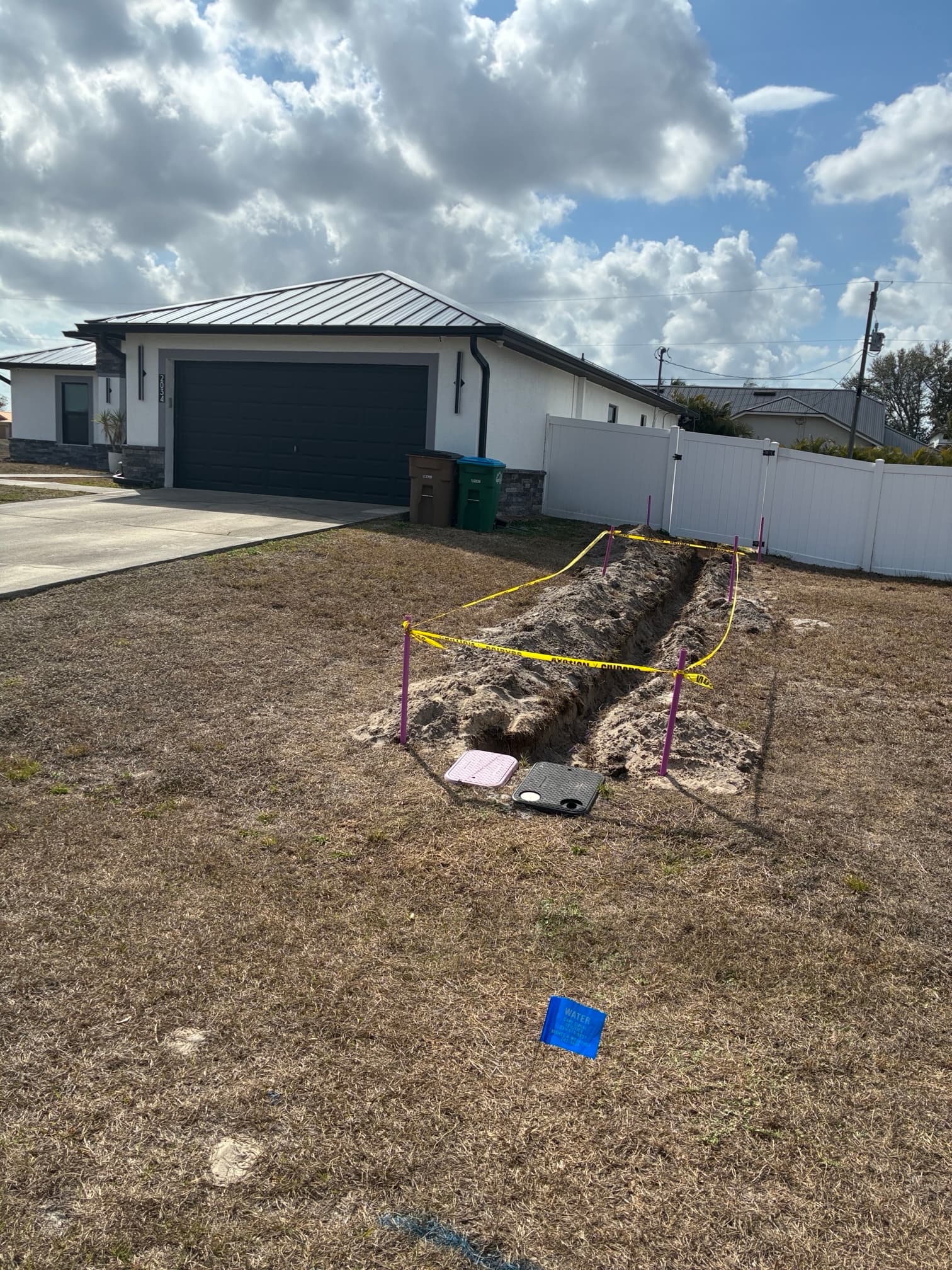 Septic abandonment trench excavation in front yard with caution tape and safety barriers