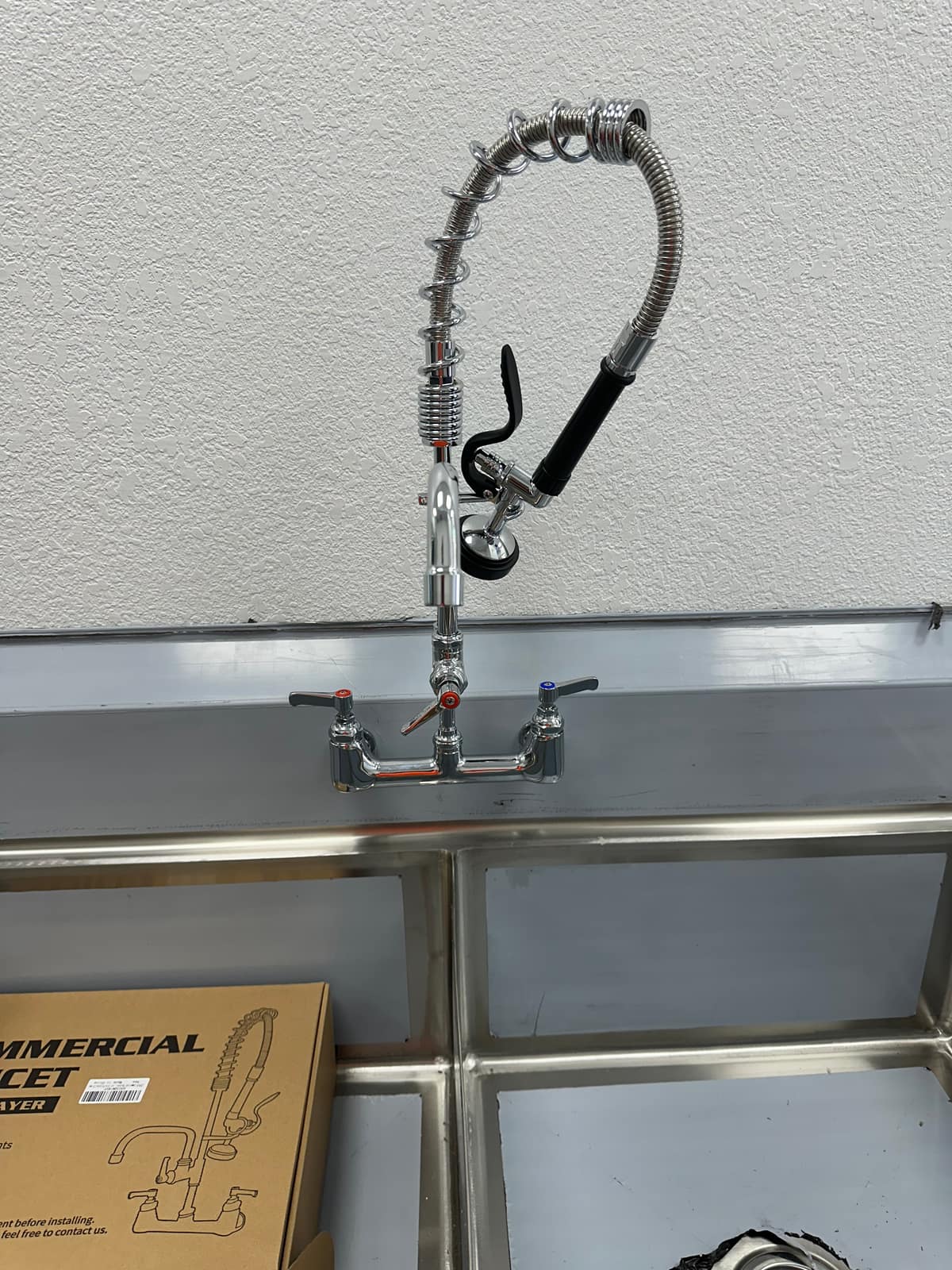Pre-rinse spray faucet installed at a commercial three-compartment sink