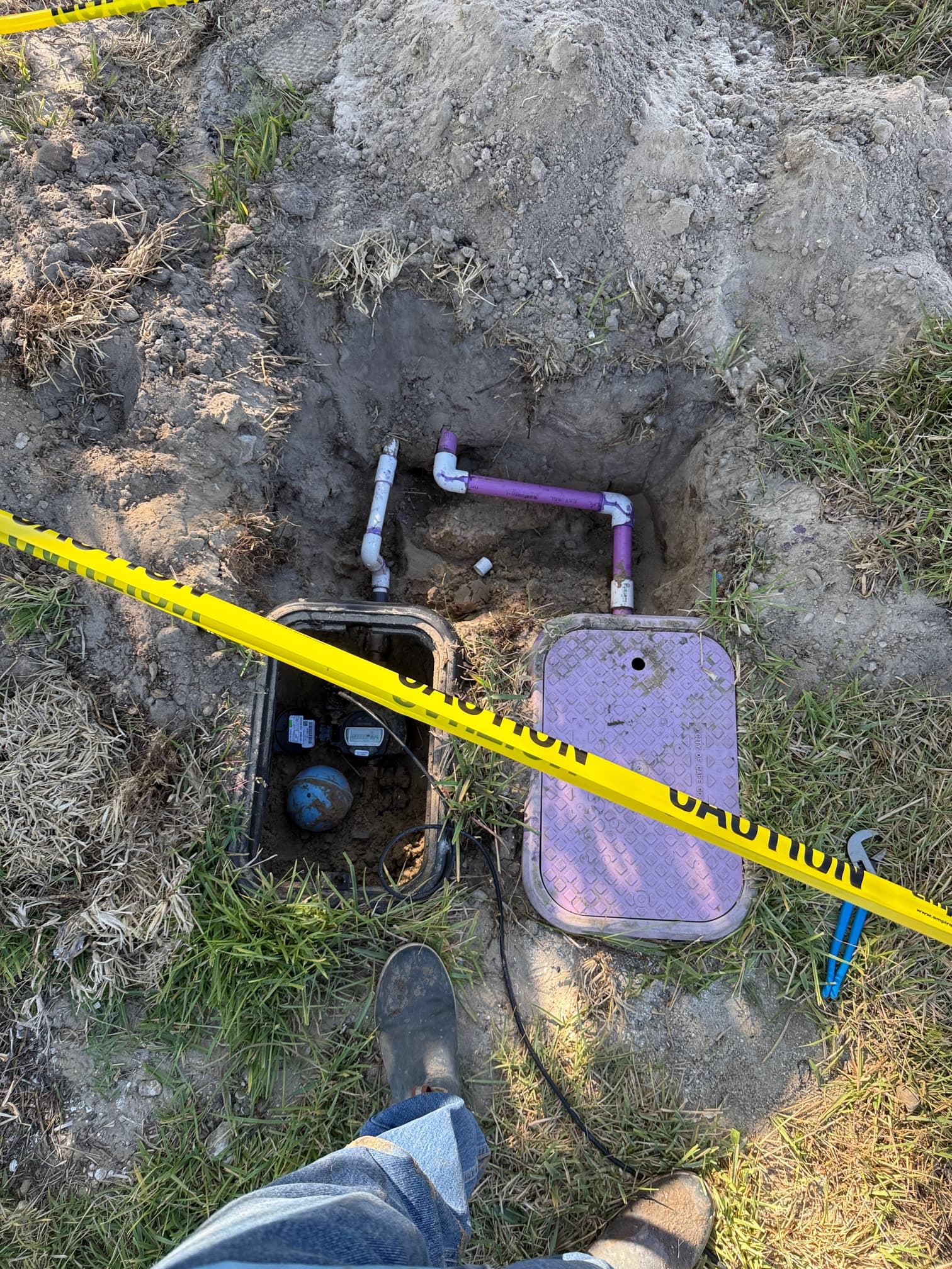 Water meter box and irrigation valve box installed with caution tape — freshly completed UEP hookup